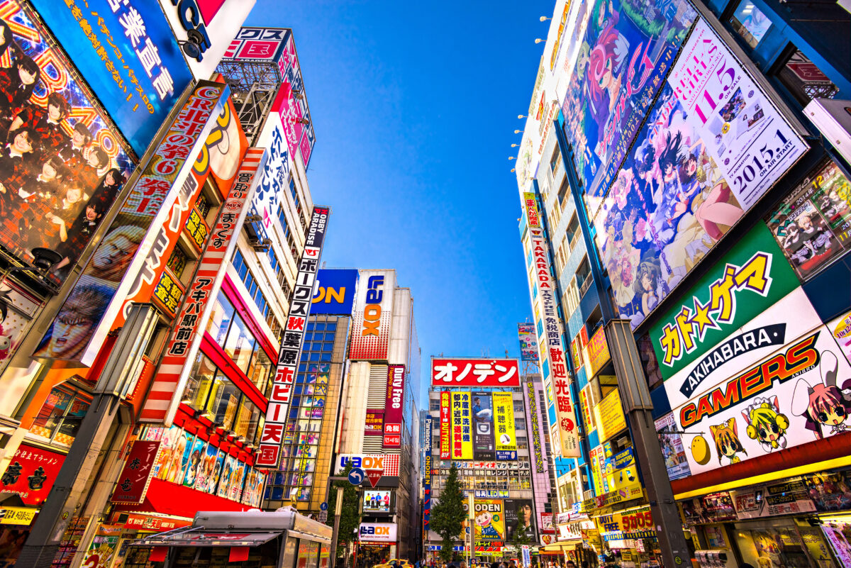 Neon-lit streets of Akihabara district with anime billboards and electronics stores at night