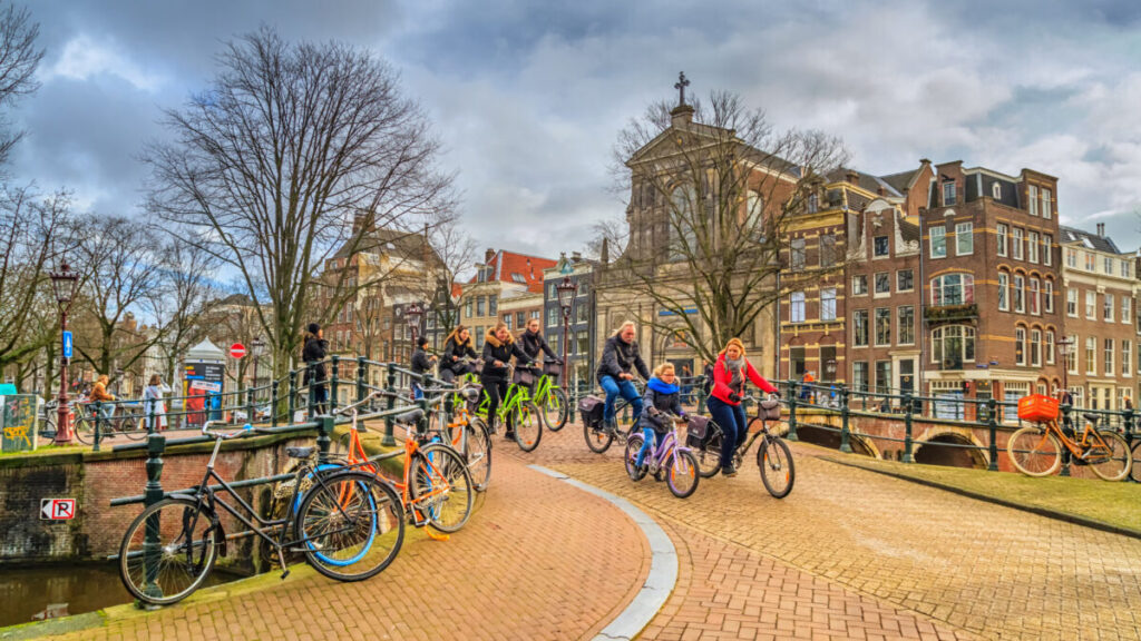 Group of locals and tourists biking along the historic center of Amsterdam in the Netherlands