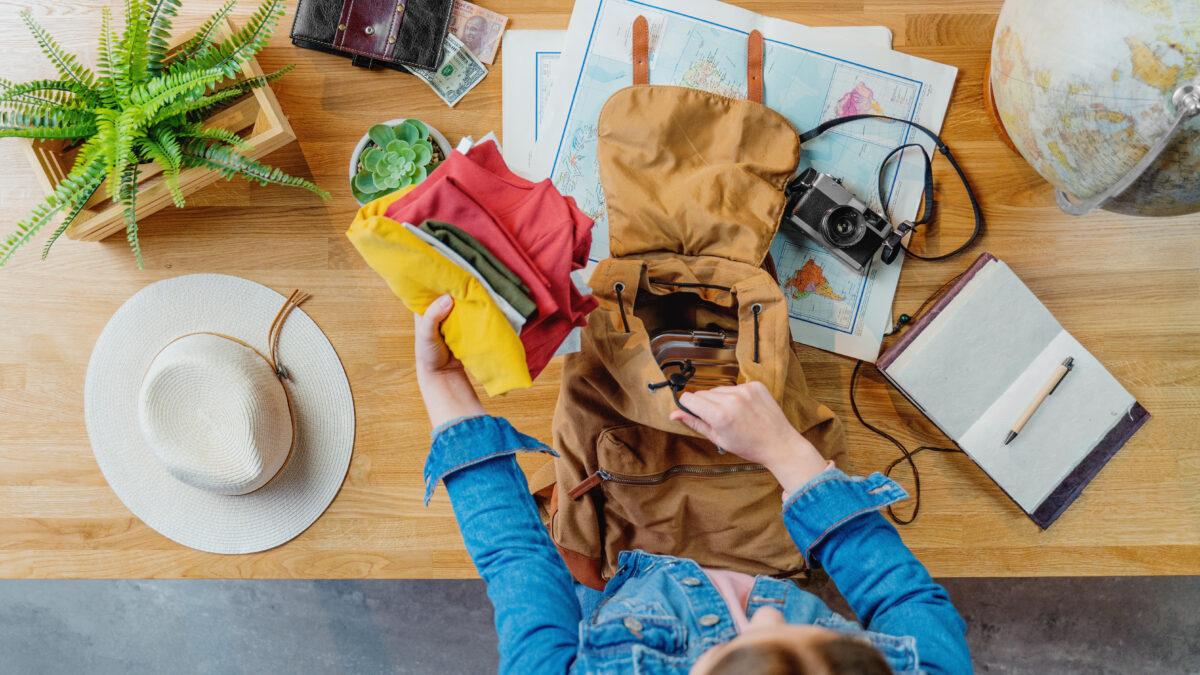 Woman busy packing clothes and travel essentials on a backpack