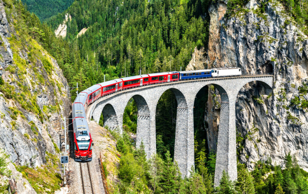 Bernina Express train passing by the Landwasser Viaduct railway bridge in Switzerland Swiss Alps