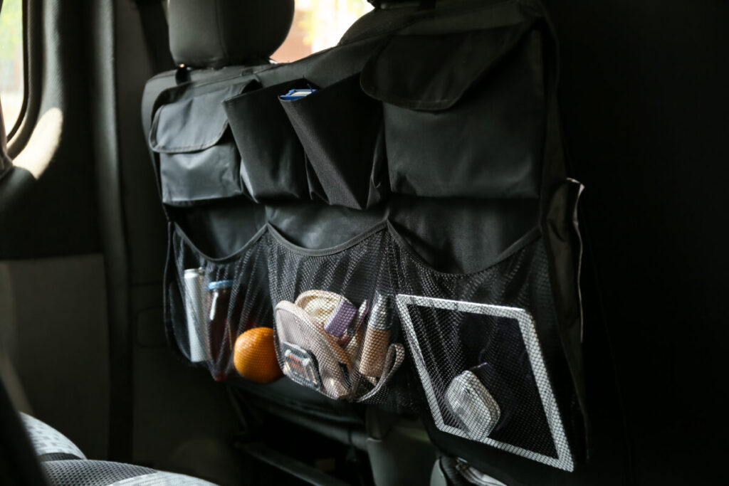 Close-up of a travel organizer on a car seat, displaying an assortment of travel essentials and accessories for convenience