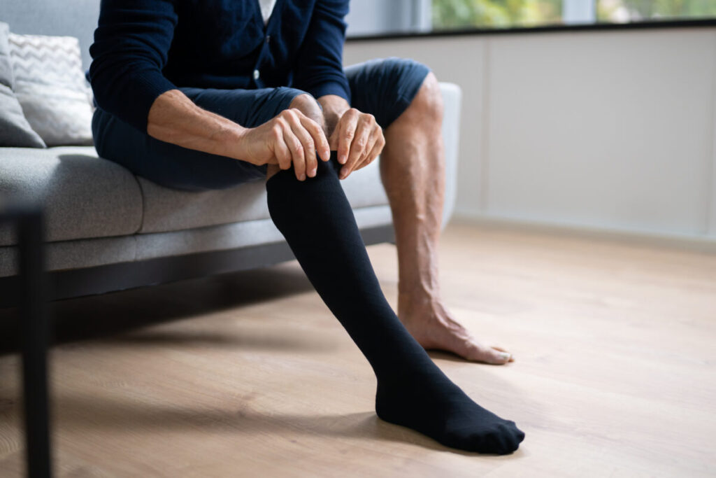 Man putting on a color black medical compression socks or stockings 