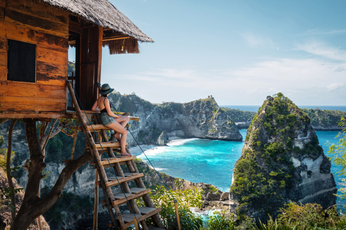 Young female traveler looking at the view of Diamond Beach at Nusa Penida Island in Bali, Indonesia