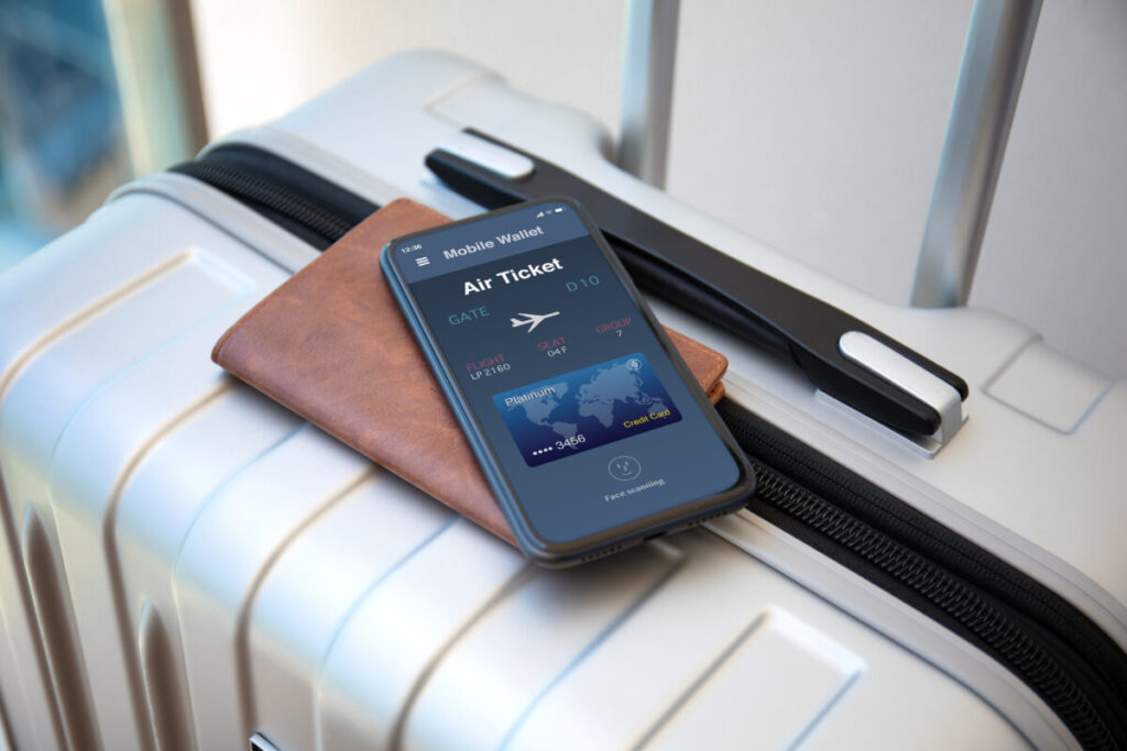 Phone displaying an air ticket application on the screen, with suitcases at the airport showing a digital copy