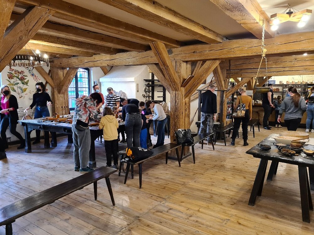 Visitors engage in a fun gingerbread activity inside the Gingerbread Museum, surrounded by festive decorations in Toruń, Poland
