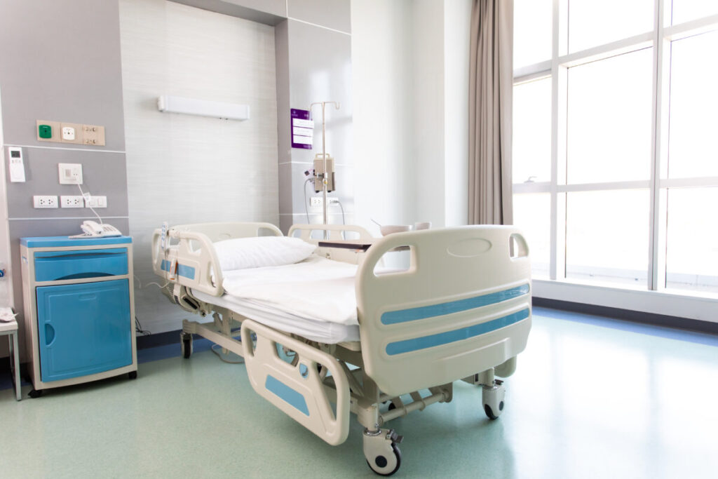 Empty clean and empty hospital room with a bed next to a huge window