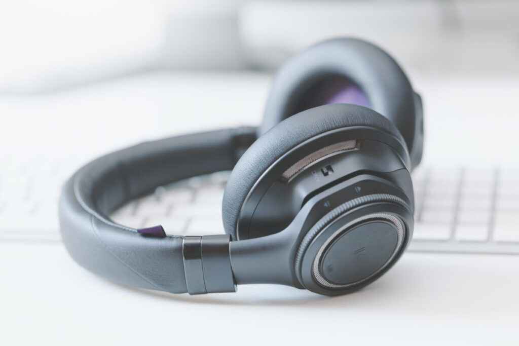 Close-up of a noise-cancelling headphones on a table next to a keyboard