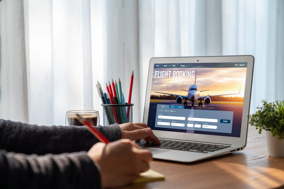 Man using a laptop to book a flight on an online flight booking website