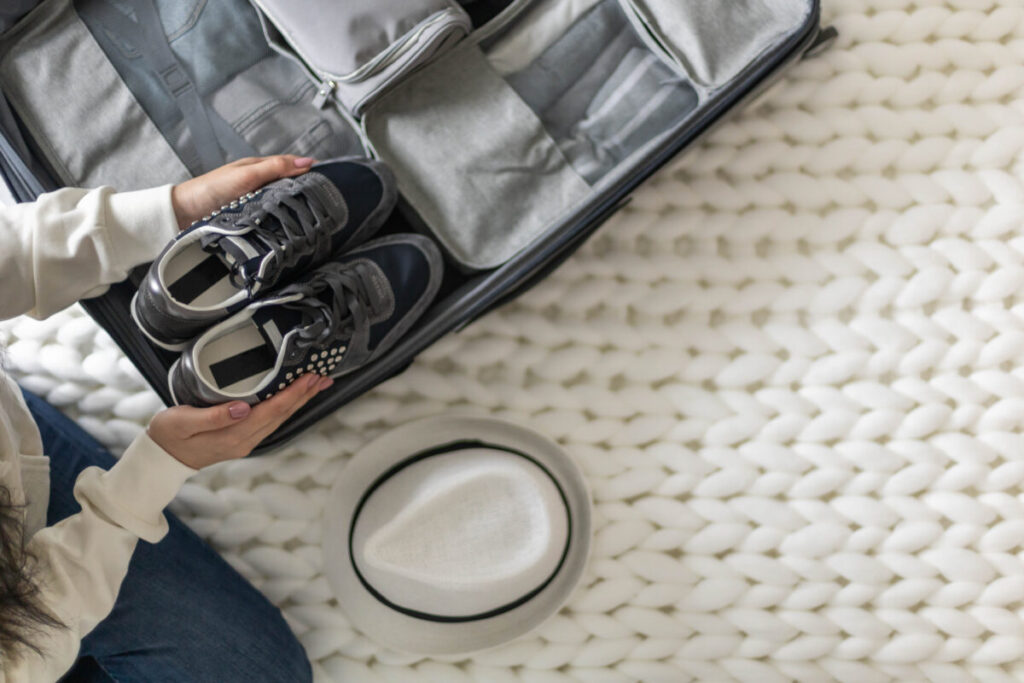 Woman holding a pair of shoes, ready to pack them into a suitcase for travel