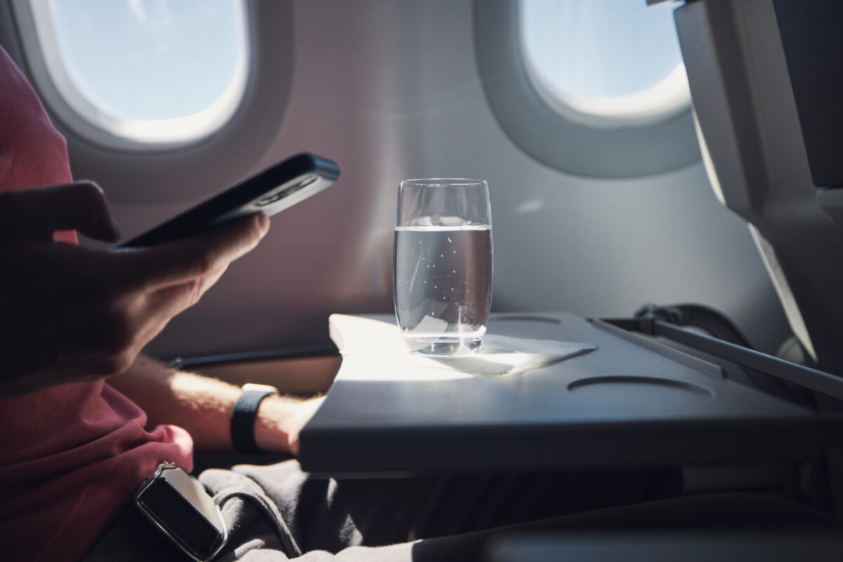 Clear glass of water resting on the table of an airplane seat