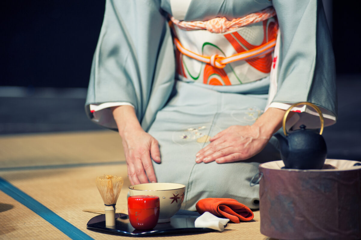 Japanese tea master in blue kimono performing traditional matcha tea ceremony