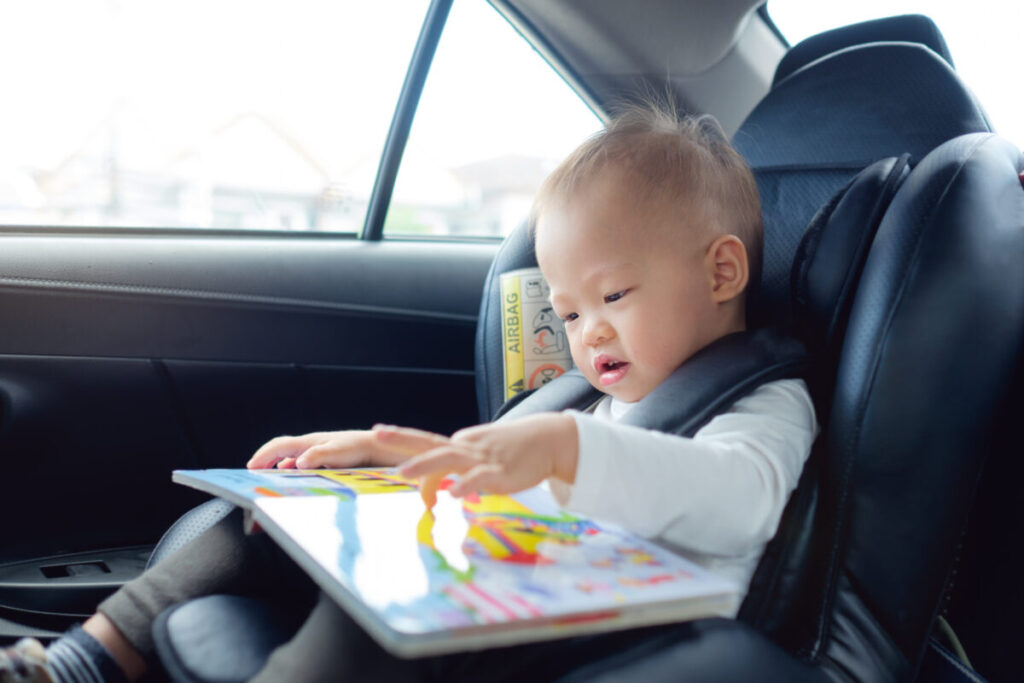 Close-up of a small child being entertained by reading a book on a car ride