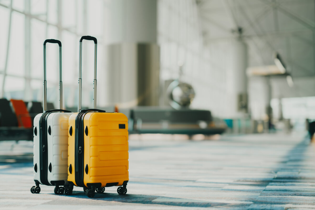 Close-up of two suitcases in color yellow and white in an empty airport hall