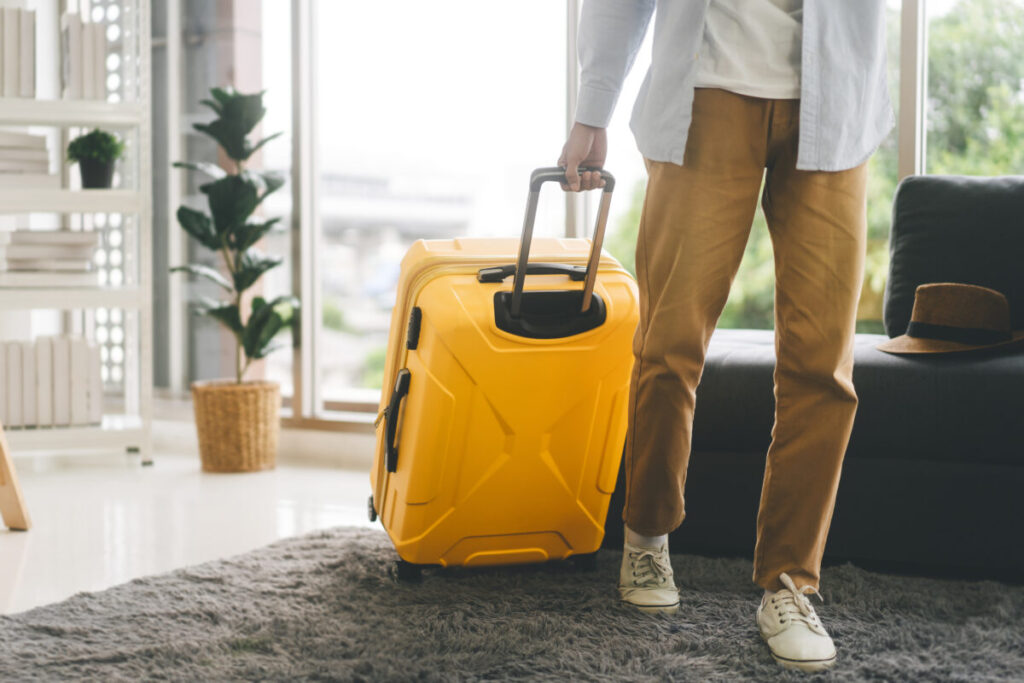 Close-up of man pulling a yellow luggage ready to travel