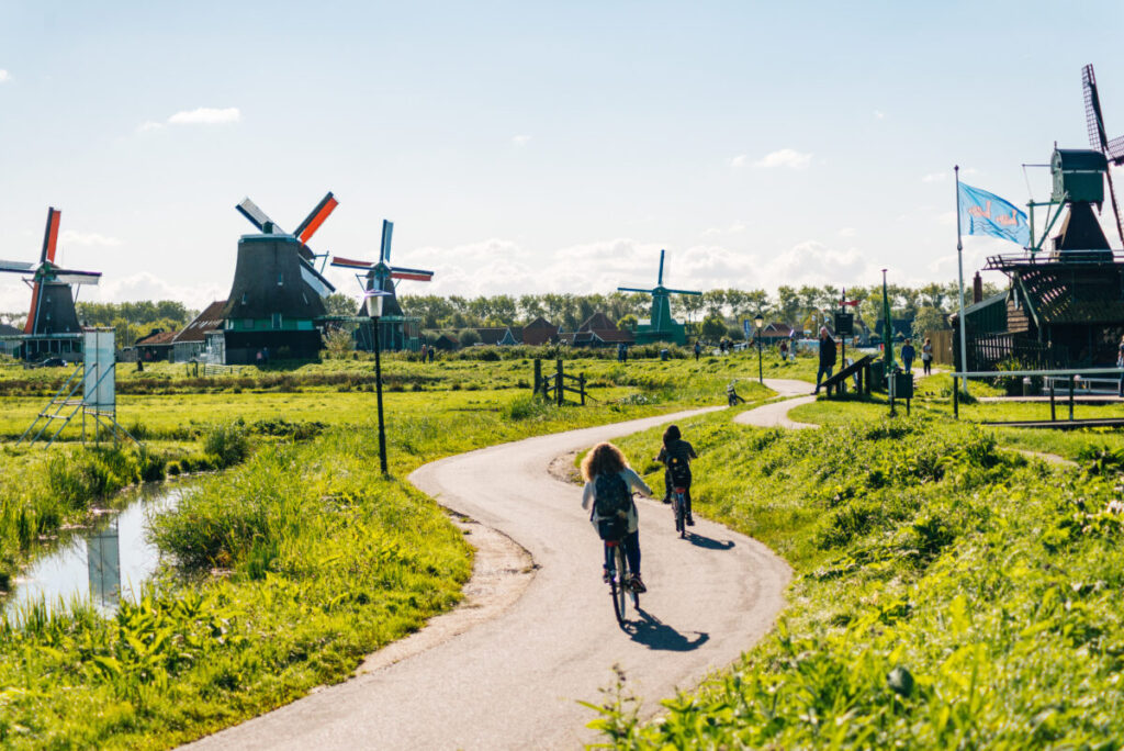 Two tourists biking and exploring the Zaanse Schans windmills  and beauty in the Netherlands